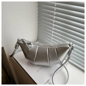 Detail of silver pleated crescent bag showing metallic finish and knotted shoulder strap