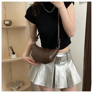 Détail d'un sac bandoulière marron foncé en forme de croissant avec plis surpiqués