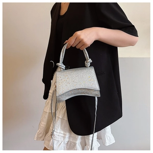 Detail of silver sequin texture and knotted handle on the stylish hourglass shaped handbag