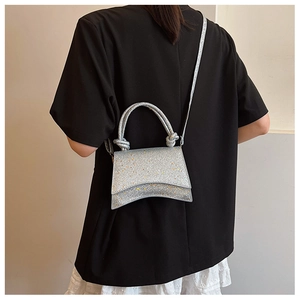 Detail of silver sequin bag featuring a unique curved base and knotted handle texture
