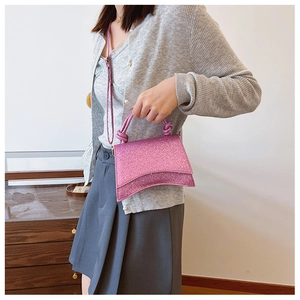 Detail of a pink glitter handbag with a curved base and a stylish knotted top handle