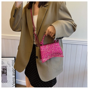 Detailed view of pink sequined handbag with curved base on tan blazer jacket