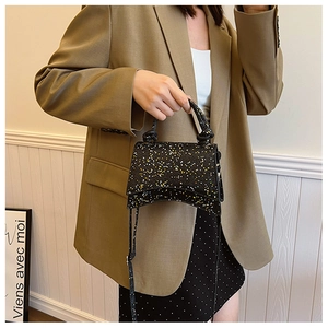 Close-up of black sequined hourglass bag with textured finish and knotted handle detail