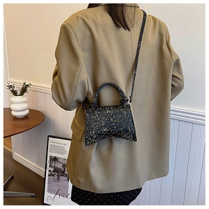 Detail view of the black sequin hourglass bag with curved base on khaki blazer