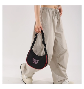 Détail du sac croissant noir avec imprimé papillon rose et bordure contrastée rouge