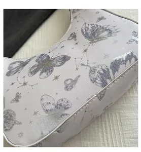 Detail of white lychee leather handbag featuring purple butterfly and silver constellation