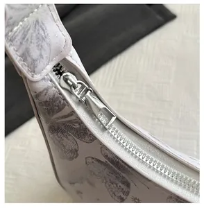 Close-up of smooth silver metal zipper on floral butterfly print leather armpit bag