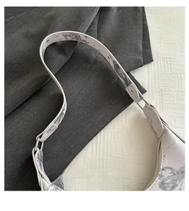 Detail of white PU leather bag featuring a wide printed strap and silver metal buckle