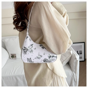 Detail of white hobo bag with silver butterfly print worn on model's shoulder
