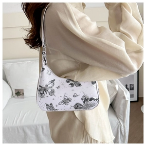 Detailed side view of elegant white bow-shaped shoulder bag with black butterfly prints