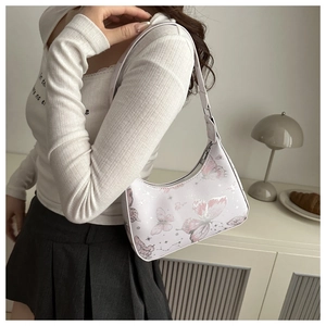 Close-up of white butterfly print hobo bag worn by a model in a cozy indoor setting