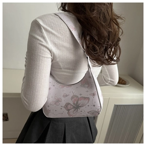 Detail of half-moon underarm bag with vintage butterfly print worn over a white outfit