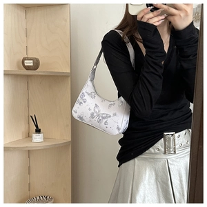 Mirror selfie showing a white hobo bag with silver butterfly prints and adjustable strap