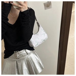 Detail of white butterfly print hobo bag paired with a silver metallic pleated skirt