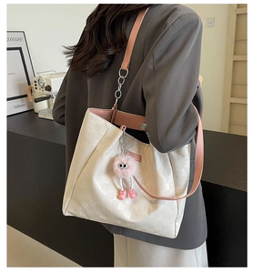 Detail of white checkered tote bag with pink straps and plush charm on a shoulder