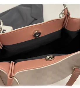 Detail of silver magnetic buckle and checkerboard embossed texture on contrast tote bag