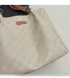 Close-up of beige checkered tote bag with fashion tag and metal chain strap detail