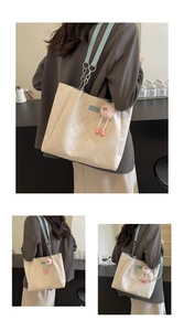 Detail of checkered tote bag with blue strap and cute plush monster charm accessory