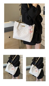 Detail of checkered tote bag with pink monster plush charm and metal chain strap