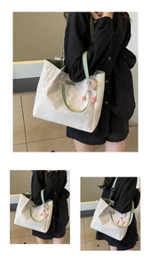 Detail of white checkered tote bag with green straps and pink plush pendant