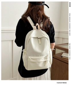 Detail view of a white minimalist backpack with smooth matte texture and adjustable straps