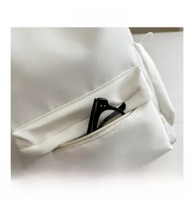 Detailed close-up of cream white waterproof nylon backpack featuring a front zipper pocket