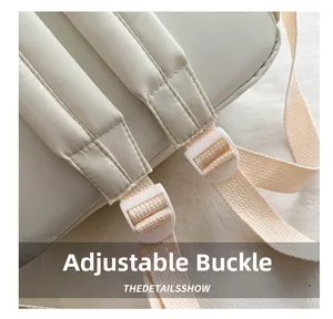 Detail showing the adjustable white buckle and reinforced strap of the cream school backpack