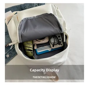 Internal capacity display of a white nylon backpack showing an umbrella, tablet, and wallet