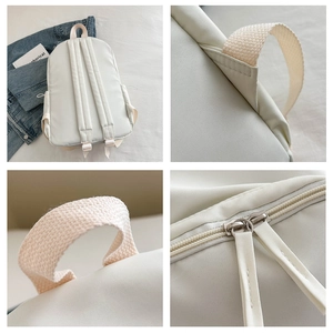 Detail view of white nylon backpack featuring woven handles and durable metal zippers
