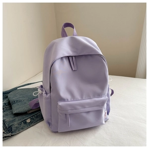 Detail view of purple oxford backpack with front zipper pocket on white bedding background