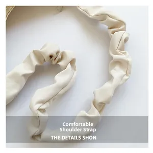 Close-up of cream pleated shoulder strap with soft scrunchie texture on a handbag