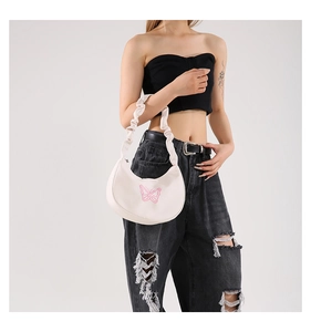 Detail of white pleated shoulder bag featuring delicate pink butterfly embroidery