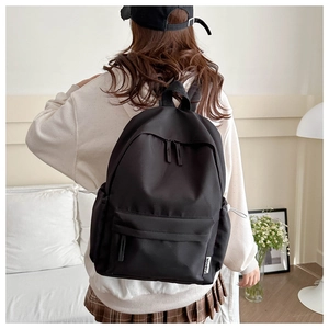 Close-up of a minimalist black nylon backpack showing side pocket and durable texture