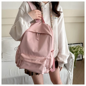 Detailed view of pink nylon backpack showing spacious front pocket and side drawstring pockets