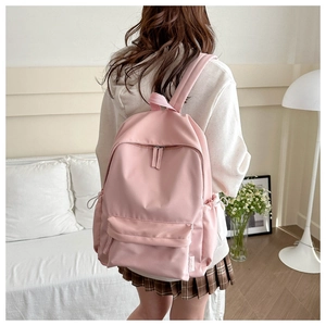 Pink minimalist backpack worn by a model in a cozy indoor lifestyle setting