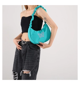 Detail of light green pleated shoulder bag with pink butterfly embroidery on model