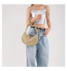 Detail of beige crescent underarm bag featuring pink butterfly embroidery and pleated strap