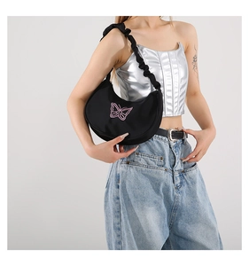 Detail of black crescent shoulder bag featuring pink butterfly embroidery and ruffled strap