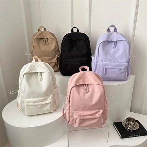 Minimalist Oxford cloth backpacks in five colors displayed on a white podium