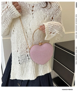 Pink heart-shaped evening bag with glitter finish, metal handle, and chain strap detail