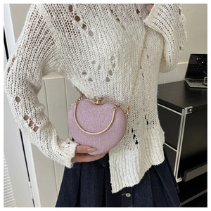 Close-up of pink heart-shaped sequin clutch with golden ring handle and chain strap