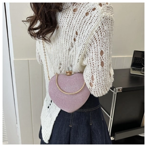Detail of pink heart-shaped evening bag featuring glitter texture and gold chain strap