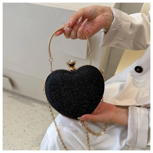 Detail of black heart-shaped evening bag featuring glitter texture and gold metal handle