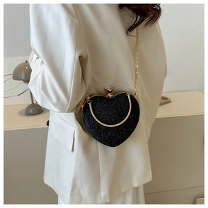 Elegant heart shaped black evening bag with gold chain worn with a white blazer