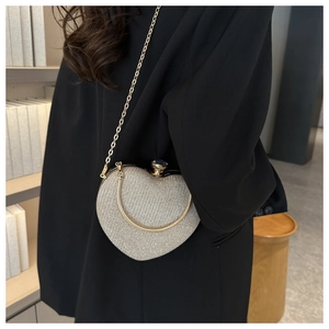 Close-up of heart-shaped evening bag in champagne gold glitter with gold chain strap