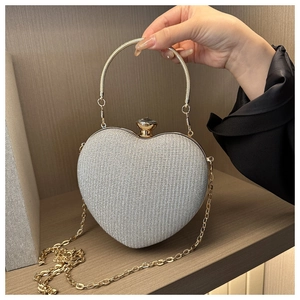 Detail of silver heart-shaped evening bag with gold ring handle and jewel clasp