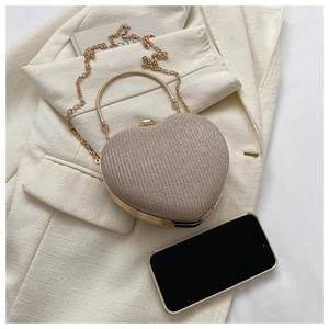 Macro detail of champagne gold heart clutch bag with glitter texture and metal handle
