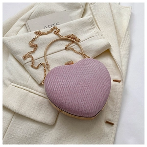 Detail of pink glitter heart evening bag with gold metal handle on beige blazer