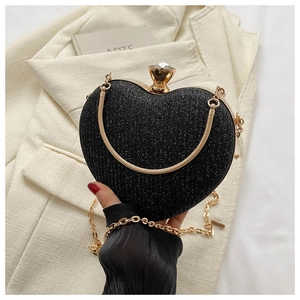 Detail of a heart-shaped evening clutch bag with black glitter finish and large crystal clasp