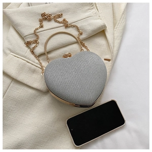 Detailed comparison of silver heart evening bag next to smartphone for size reference